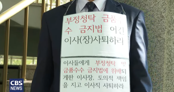이사장 사퇴하라는 피켓을 목에 걸고 시위하는  ‘학교법인 B 이사’ (사진 CBS)